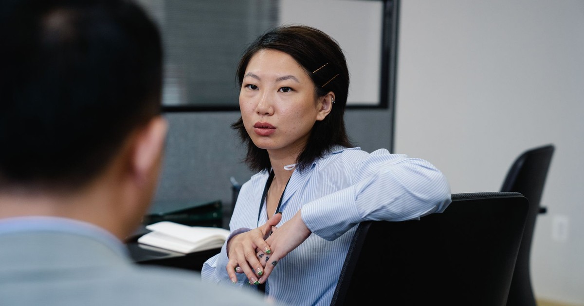Professional woman having a focused discussion in an office setting. Business attire and collaborative environment.