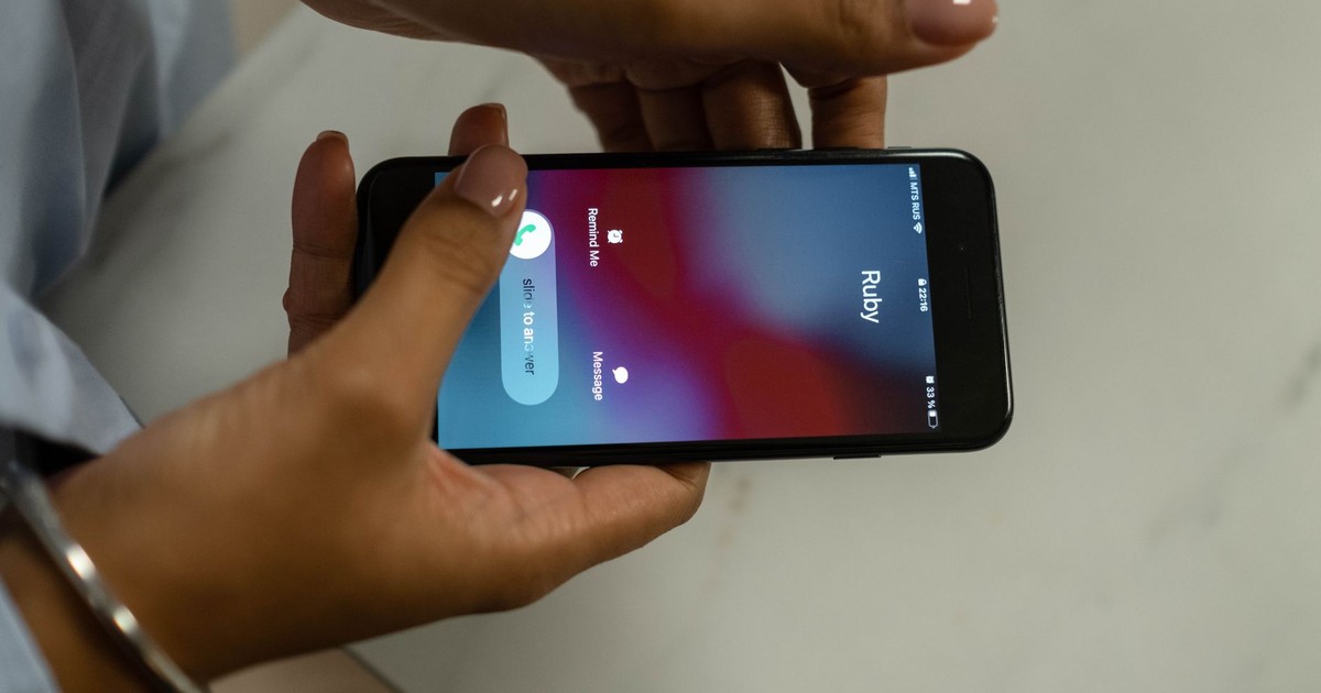 Close-up image of hands holding a smartphone receiving a call from Ruby on a marble surface.