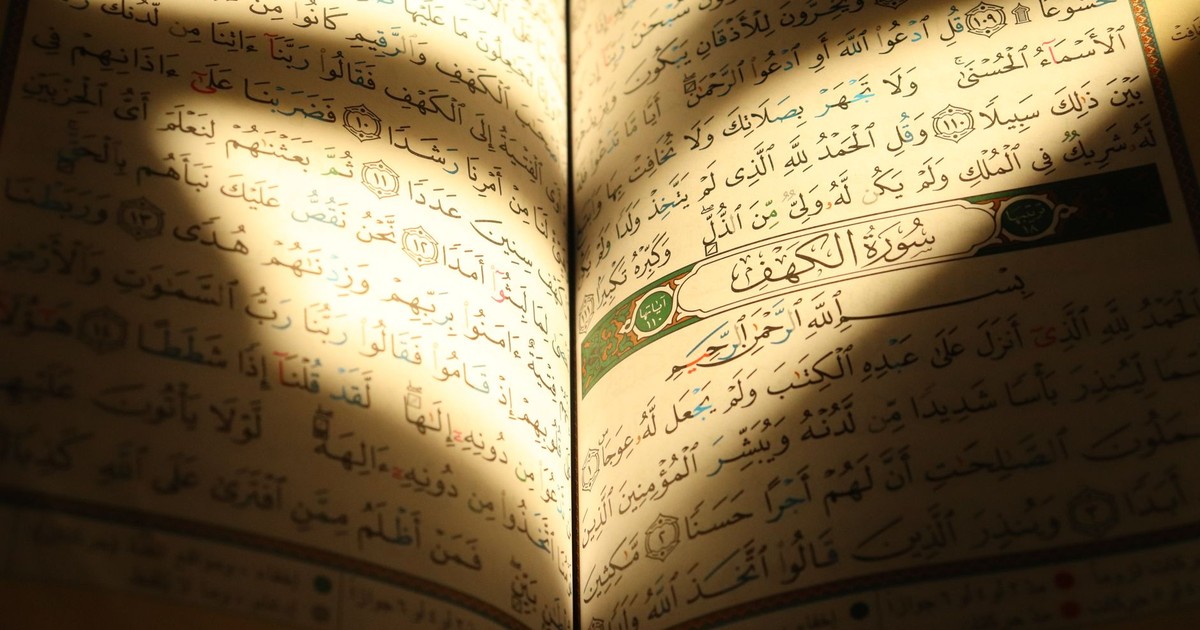 Close-up of an open Quran with sunlight highlighting Arabic text, creating a warm, reflective atmosphere.