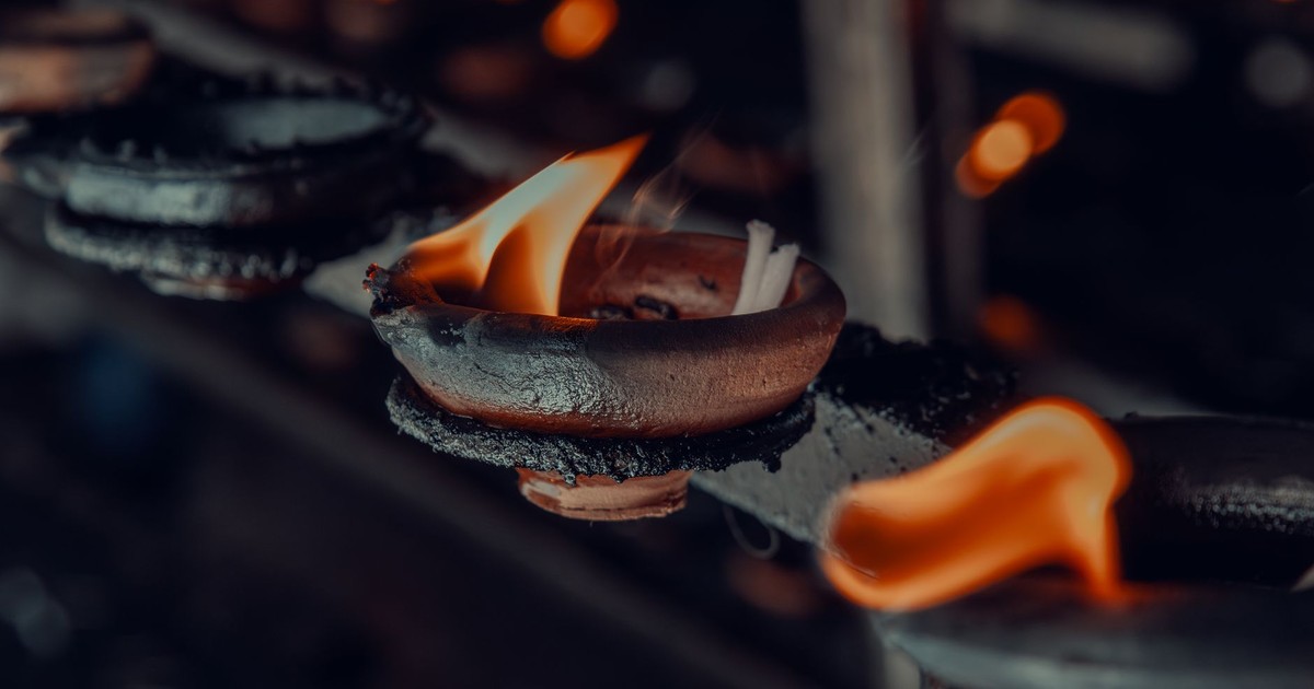 Close-up of lit oil lamps in a Sri Lankan temple, showcasing traditional Buddhist practices.