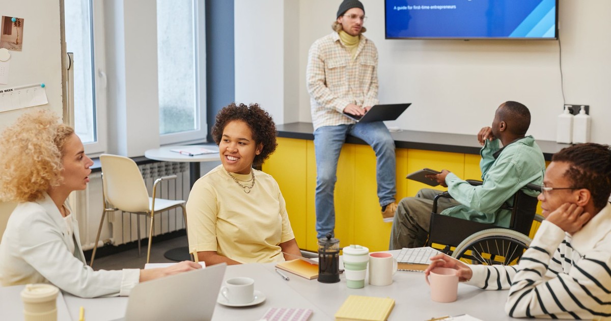 A diverse team in a modern office discussing a startup project during a workshop with a digital presentation.