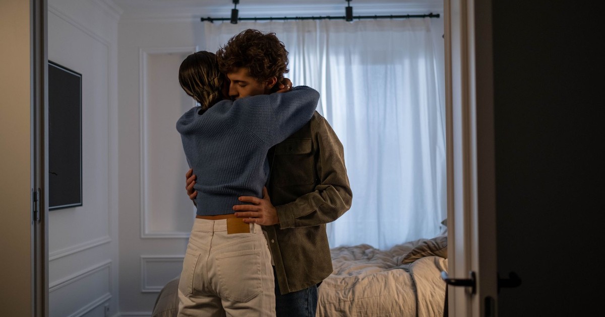 A heartfelt embrace between a loving couple in a sunlit bedroom, conveying warmth and affection.
