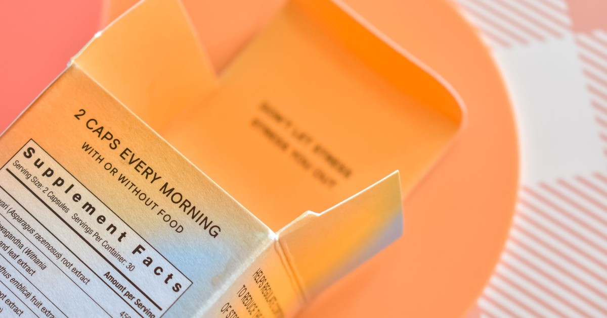 High angle view of an open supplement box on a peach-themed surface