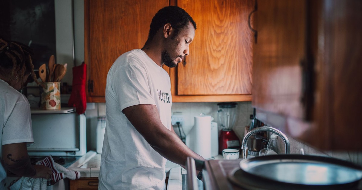 A man and woman volunteer wash dishes in a kitchen, helping their community.