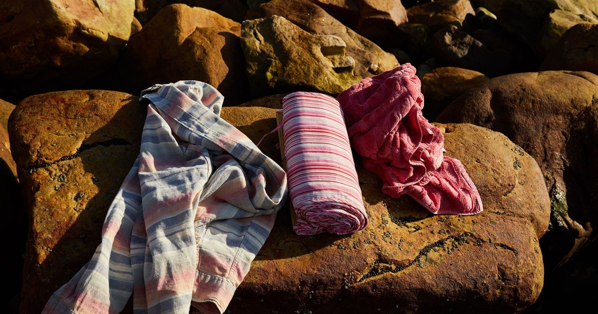 Vibrantly colored towels draped over sunlit rocks, capturing a warm outdoor setting.