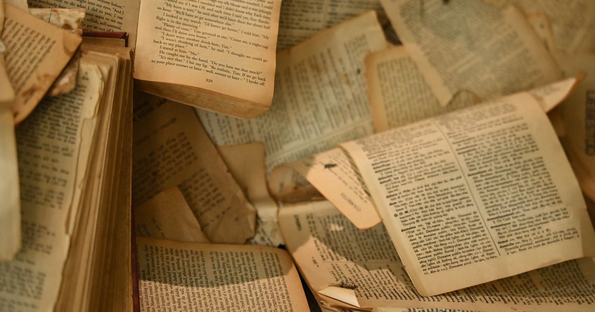 A collection of aged, open books with partially torn pages create a nostalgic atmosphere.