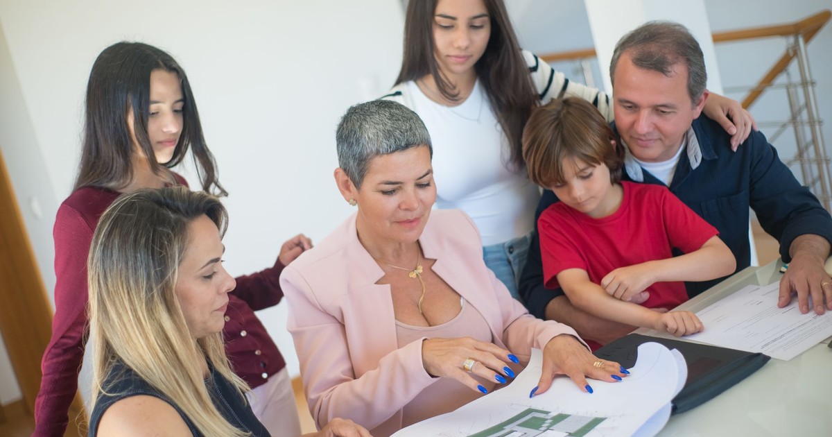 A family discusses property plans with a realtor indoors, focused on purchasing a new home.