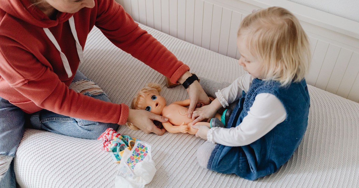 Child and adult playing with doll in cozy indoor setting, embracing childhood joy.