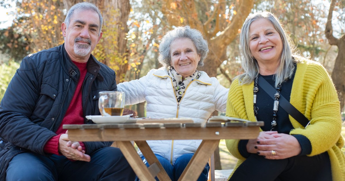 Three seniors enjoying a sunny outdoor gathering in Portugal, radiating happiness and companionship.