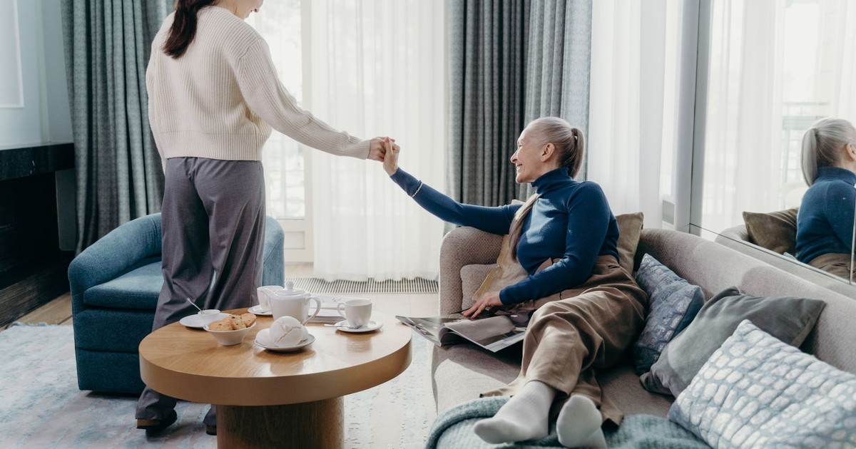 A senior woman and her adult daughter enjoy quality time relaxing at home.
