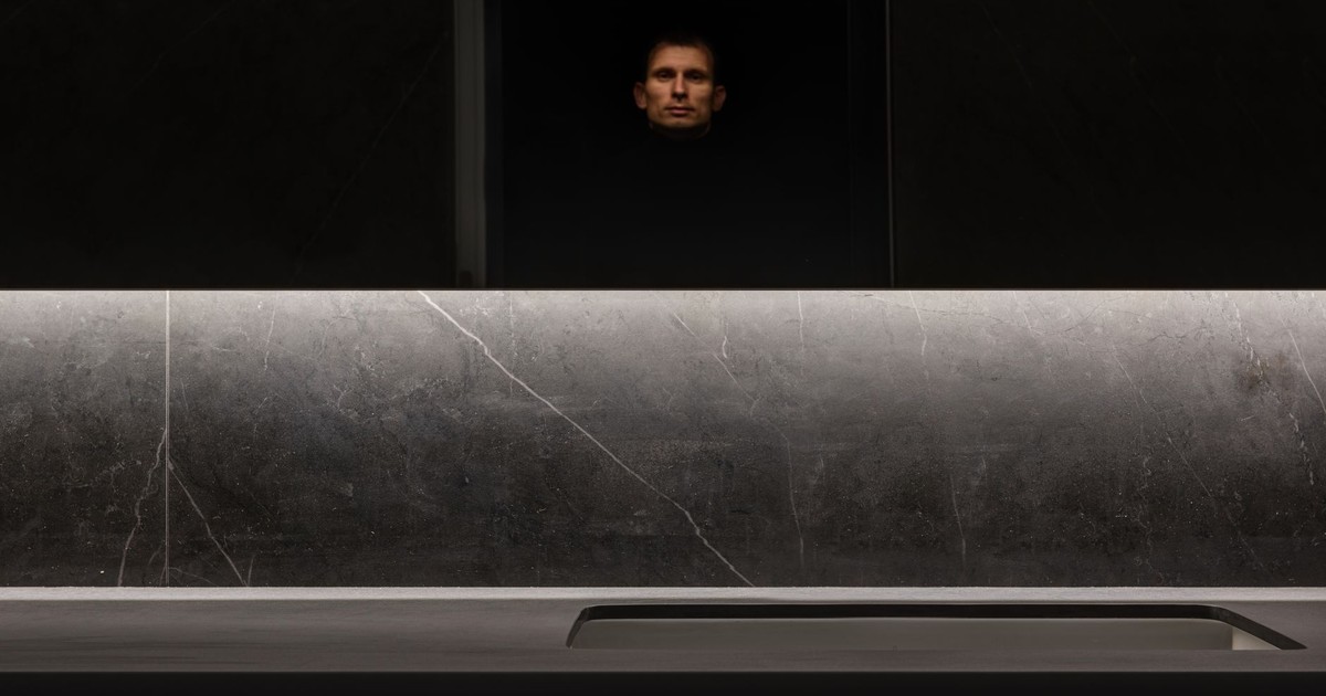 Reflection of expressive male standing in kitchen with modern design and built in sink in table
