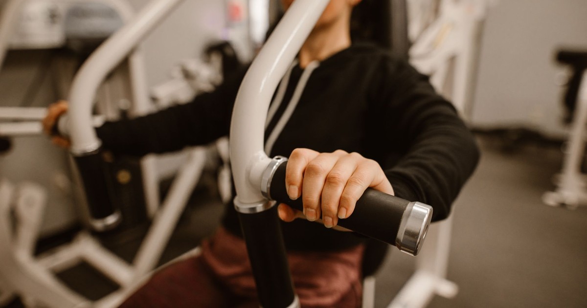 Close-up of a woman using a chest press machine in the gym for strength training.