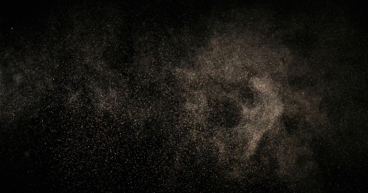 Abstract image of fine particles floating against a black background.
