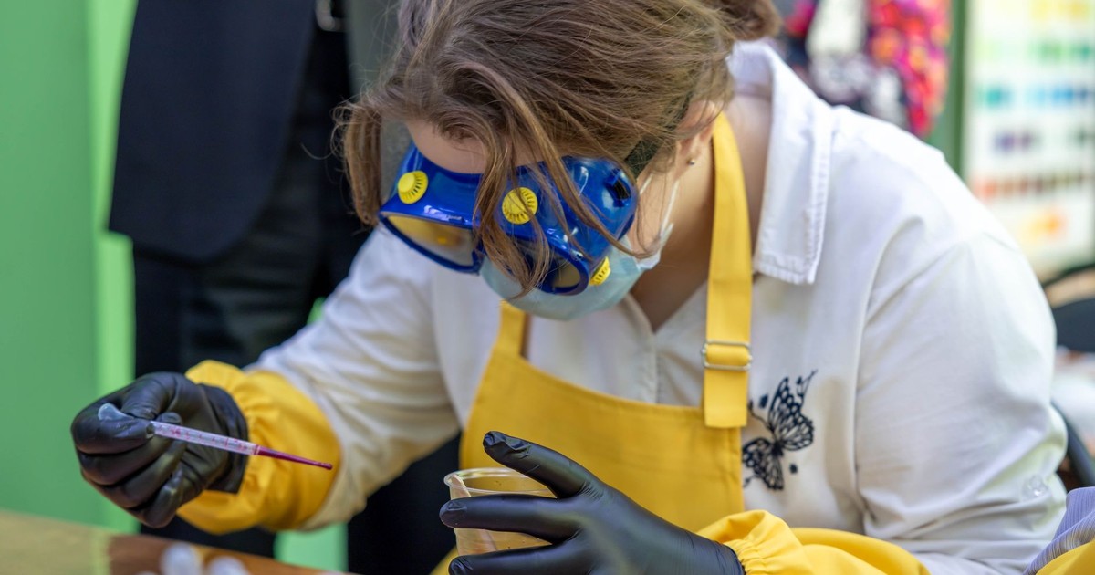 Scientist wearing safety gear conducting a precise laboratory experiment with a pipette.