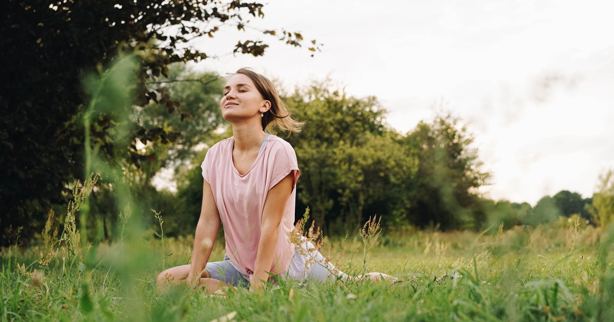 Woman practicing yoga in a serene park setting, signifying peace and mindfulness.