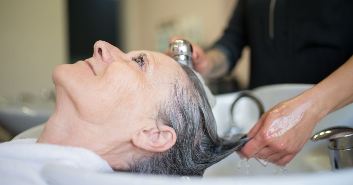 Elderly woman enjoying a relaxing hair wash session in a professional salon setting.