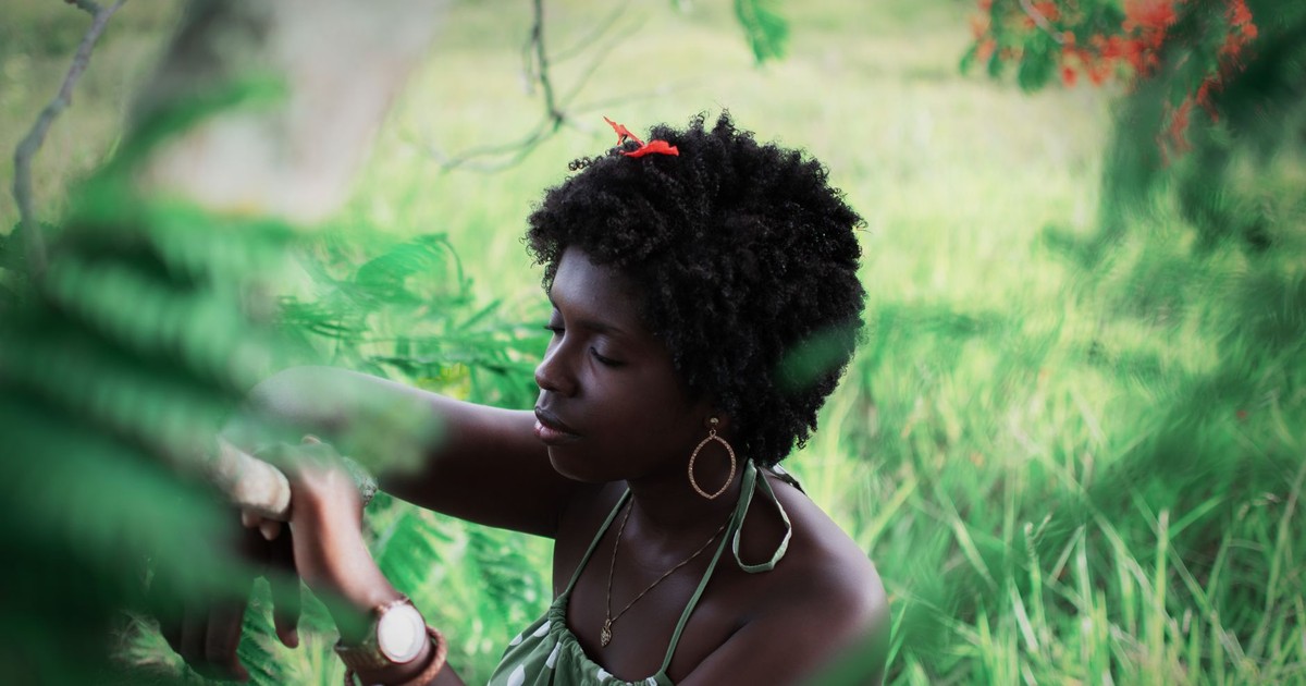 A young woman enjoying a peaceful moment in a vibrant green garden during summer.