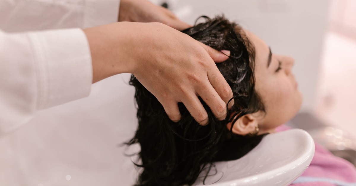 A woman enjoys a relaxing hair wash at a salon. Captured in a cozy indoor setting.