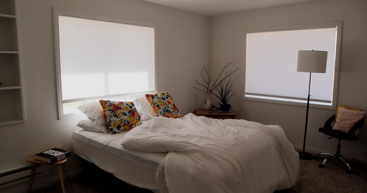 Bright and inviting modern bedroom with floral pillows and natural light.