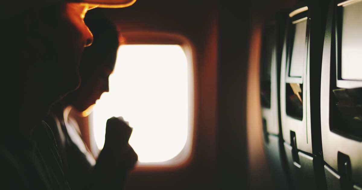 Silhouetted passengers sitting by a window during a flight, capturing a serene travel moment.