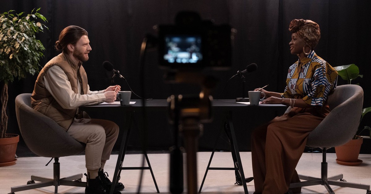 Two adults engaging in a podcast discussion in a studio with recording equipment.