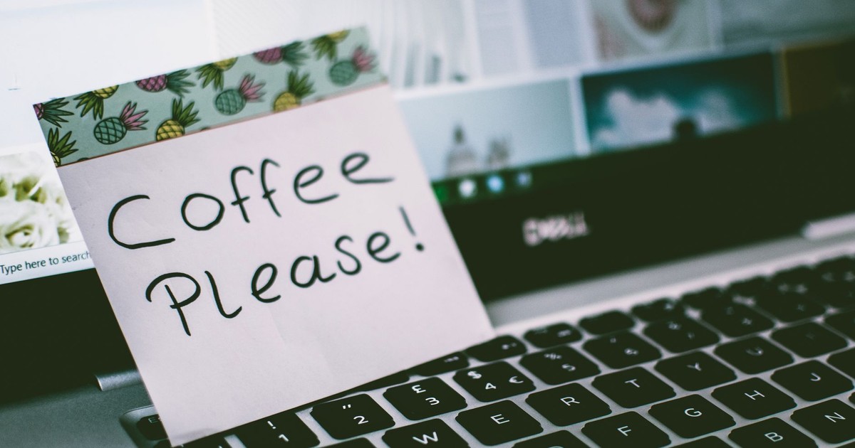 Close-up of a laptop keyboard with a note reading 'Coffee Please!' placed on top, suggesting a coffee break.