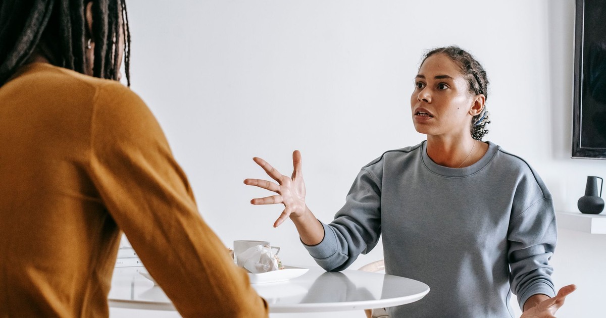 Young black woman sitting at table with man and talking to each other in modern room