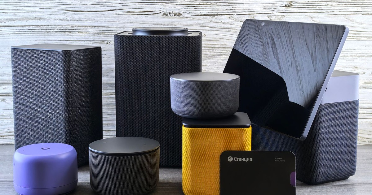A collection of various smart home speakers and tablet displayed on a wooden surface.