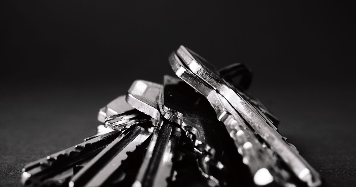 A close-up shot of a pile of metallic keys on a dark surface, emphasizing security and precision.