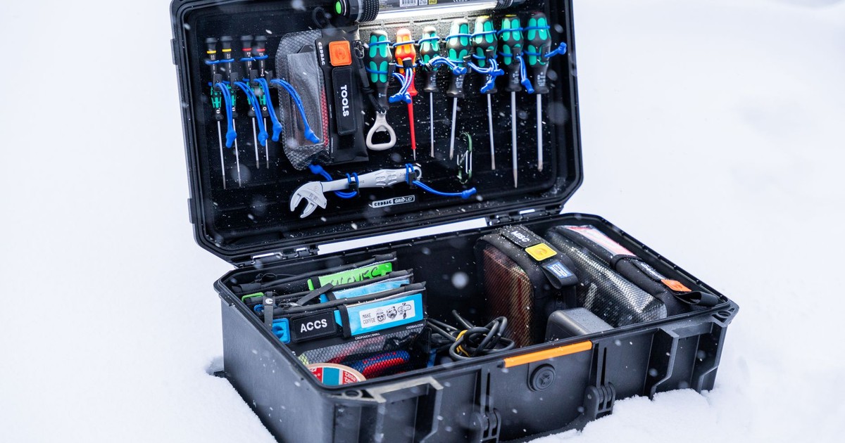 An open professional tool case filled with various tools and equipment, set in a snowy outdoor environment.