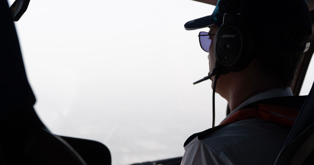 A pilot looks out the cockpit window, wearing a headset during flight.