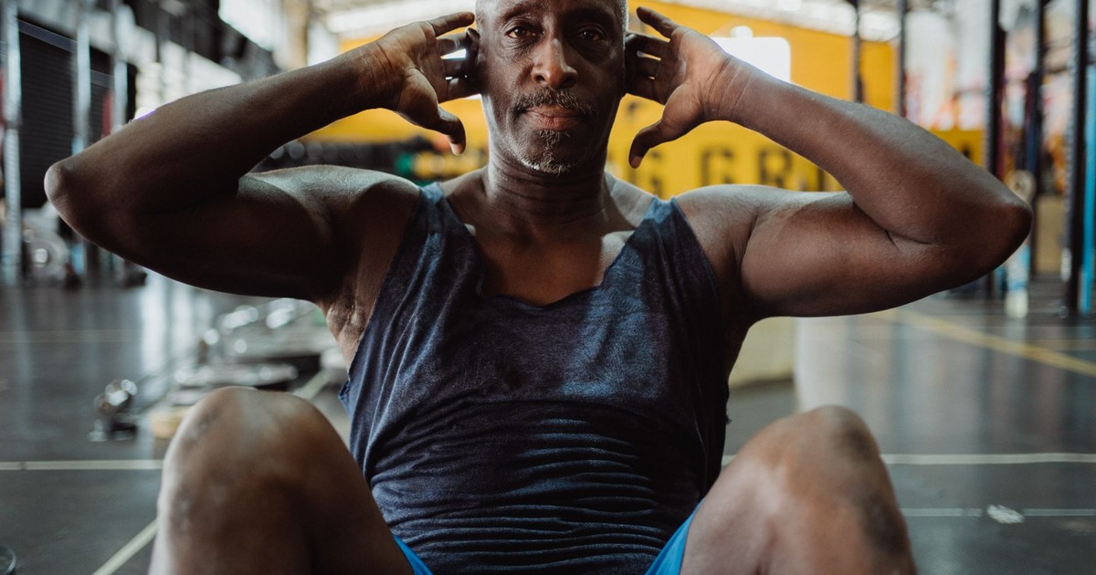 A senior man performing sit-ups in a gym, showcasing dedication to fitness.