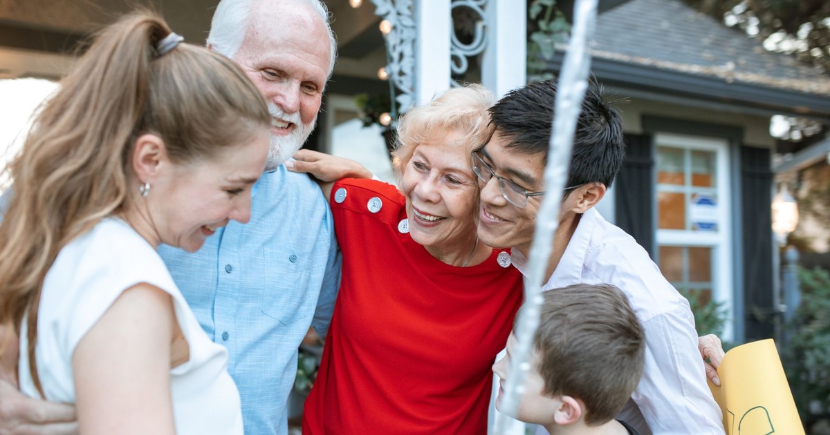 A joyful multigenerational family gathering, embracing each other outdoors with happiness.