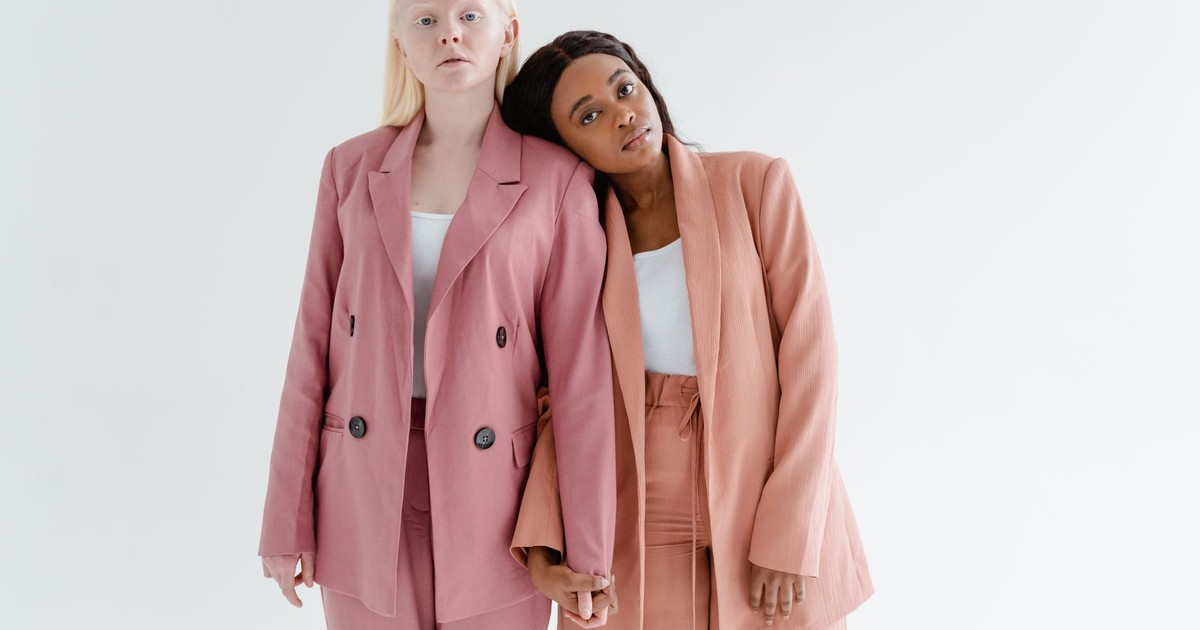 Two women in stylish blazers stand in solidarity, exemplifying unity and empowerment.