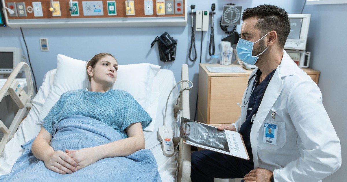 A medical practitioner discusses health details with a patient in a hospital setting.