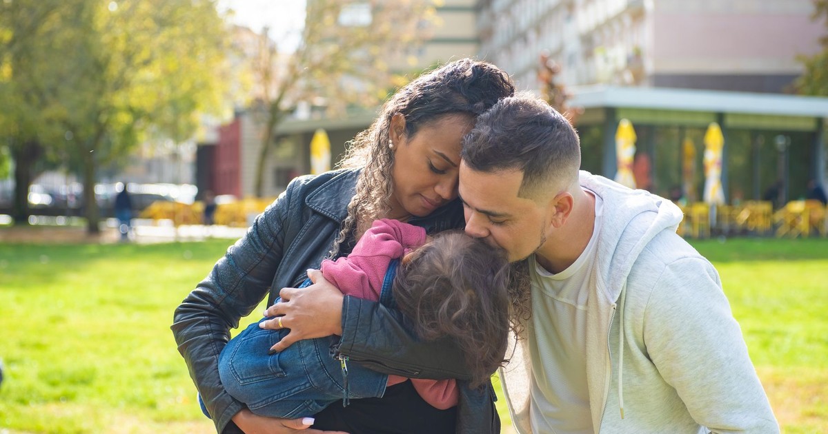 A family enjoying a warm embrace outdoors in a sunny park setting, spreading love.