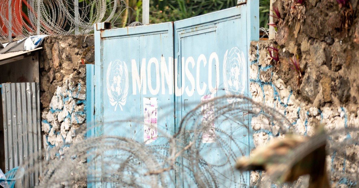Barbed wire protecting the MONUSCO gate, surrounded by stone walls and plants.