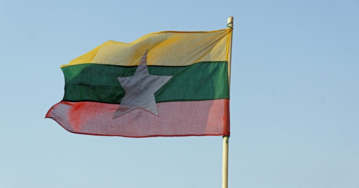 The national flag of Myanmar waving in a clear blue sky, symbolizing freedom and patriotism.