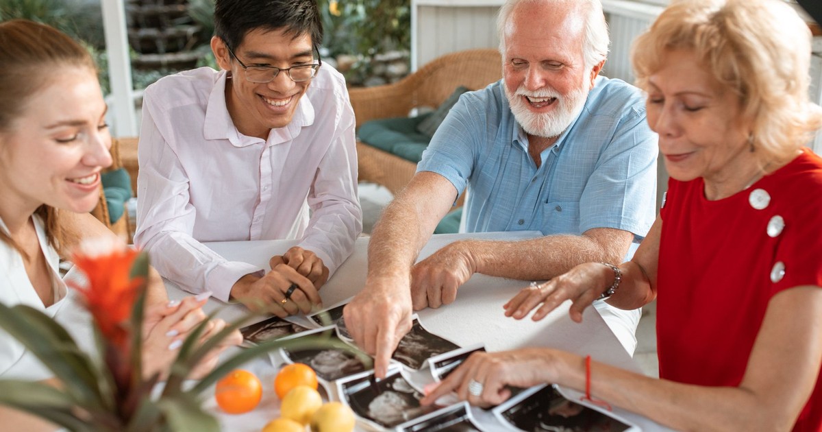 Four adults joyfully review ultrasound images at a table, celebrating a new family arrival.