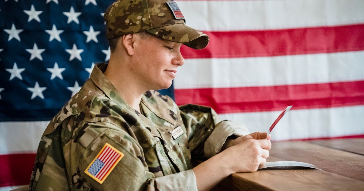 Soldier in uniform with US flag background, reflecting on memories.