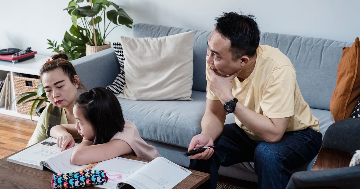 A family spends quality time studying together in a comfortable living room setting.