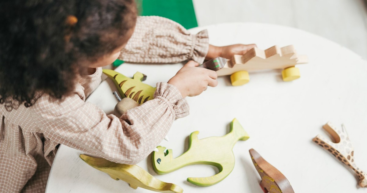 A young girl engaged in imaginative play with colorful wooden toys indoors.