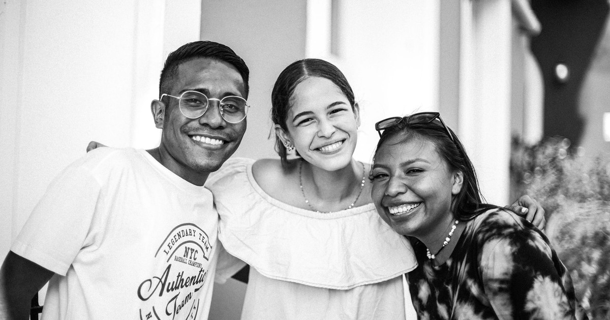 A cheerful group of friends embracing and smiling outdoors, captured in black and white.