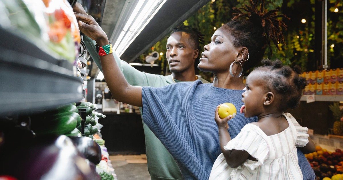 A family of three shopping in a grocery store, selecting fresh produce together.