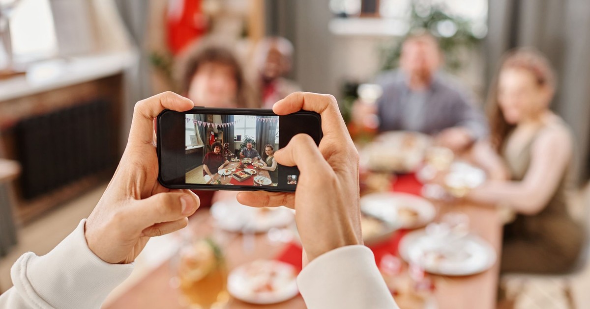A smartphone captures a group enjoying a festive meal together indoors.