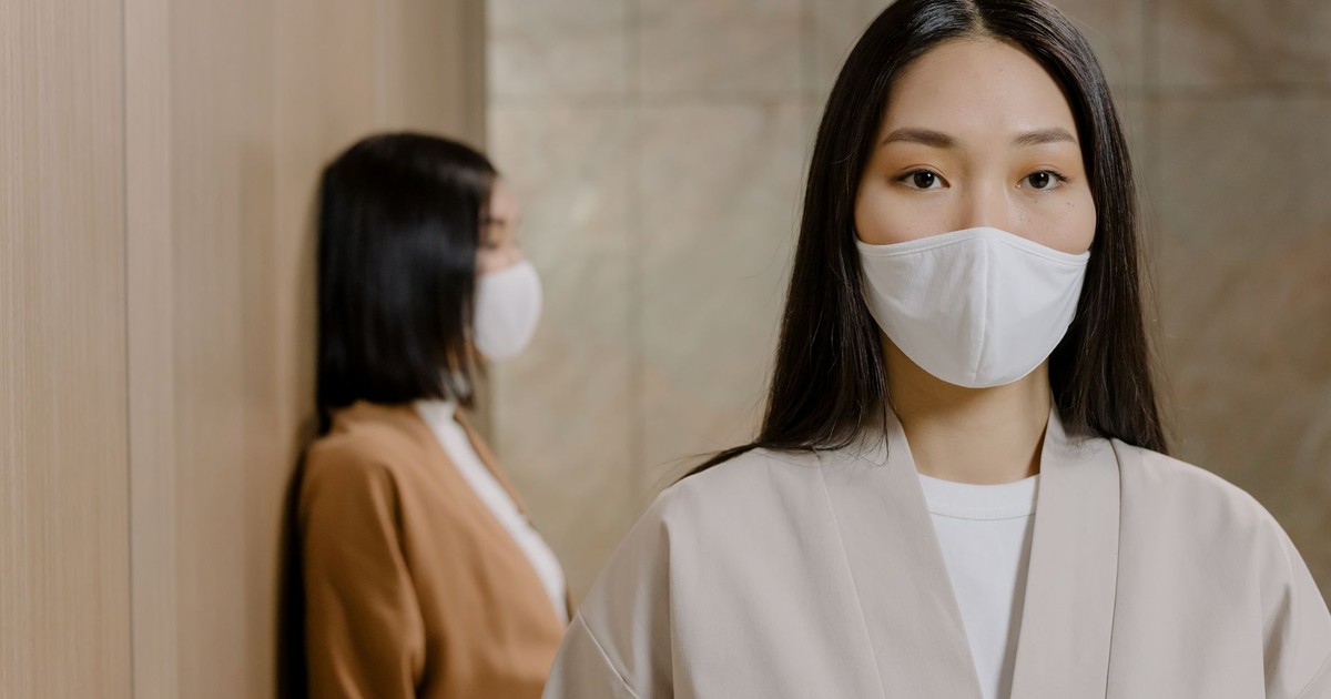 Portrait of an Asian woman with face mask, reflecting pandemic safety indoors.