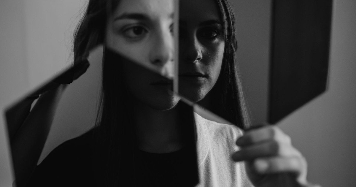 Black and white portrait exploring identity and emotion through mirror reflections.