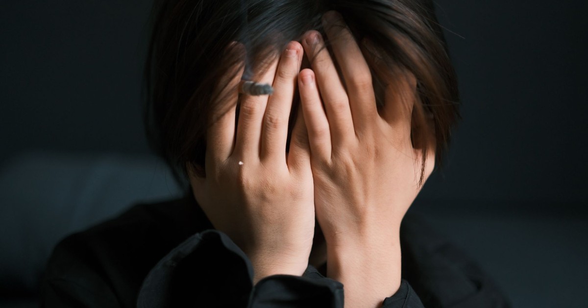 A woman with hands covering face showing emotion and stress indoors, creating a moody and introspective feel.