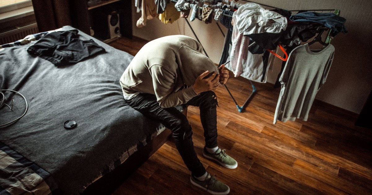 A person sits on a bed in distress, emphasizing mental health awareness.