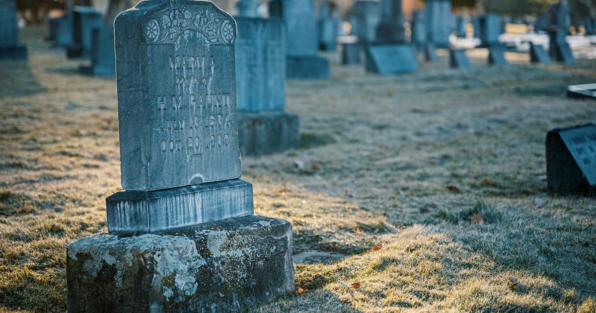 A peaceful cemetery scene featuring an old tombstone on a frosty morning.